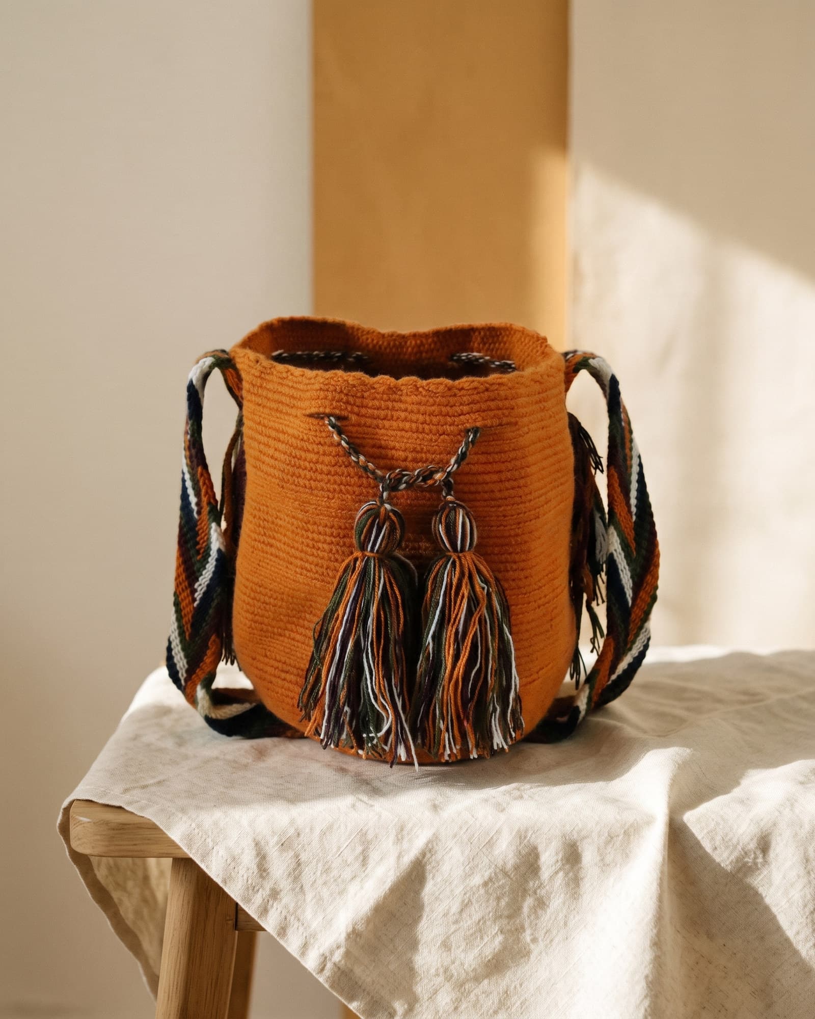 Handgewebte einfarbige Wayuu-Mochila in Terracotta-Orange auf warmem Leinen