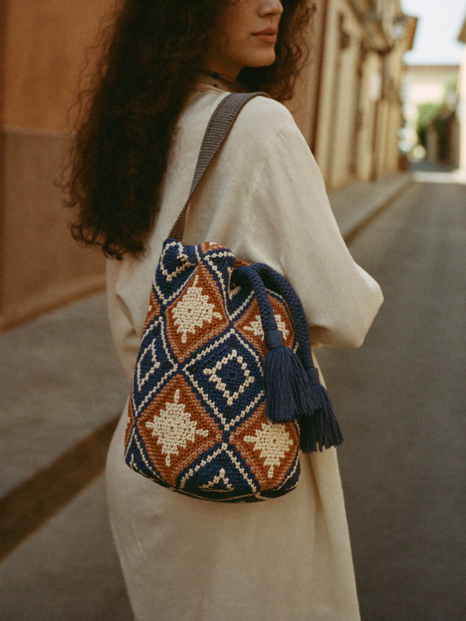Frau in Leinenkleid trägt eine handgewebte Wayuu-Mochila über der Schulter